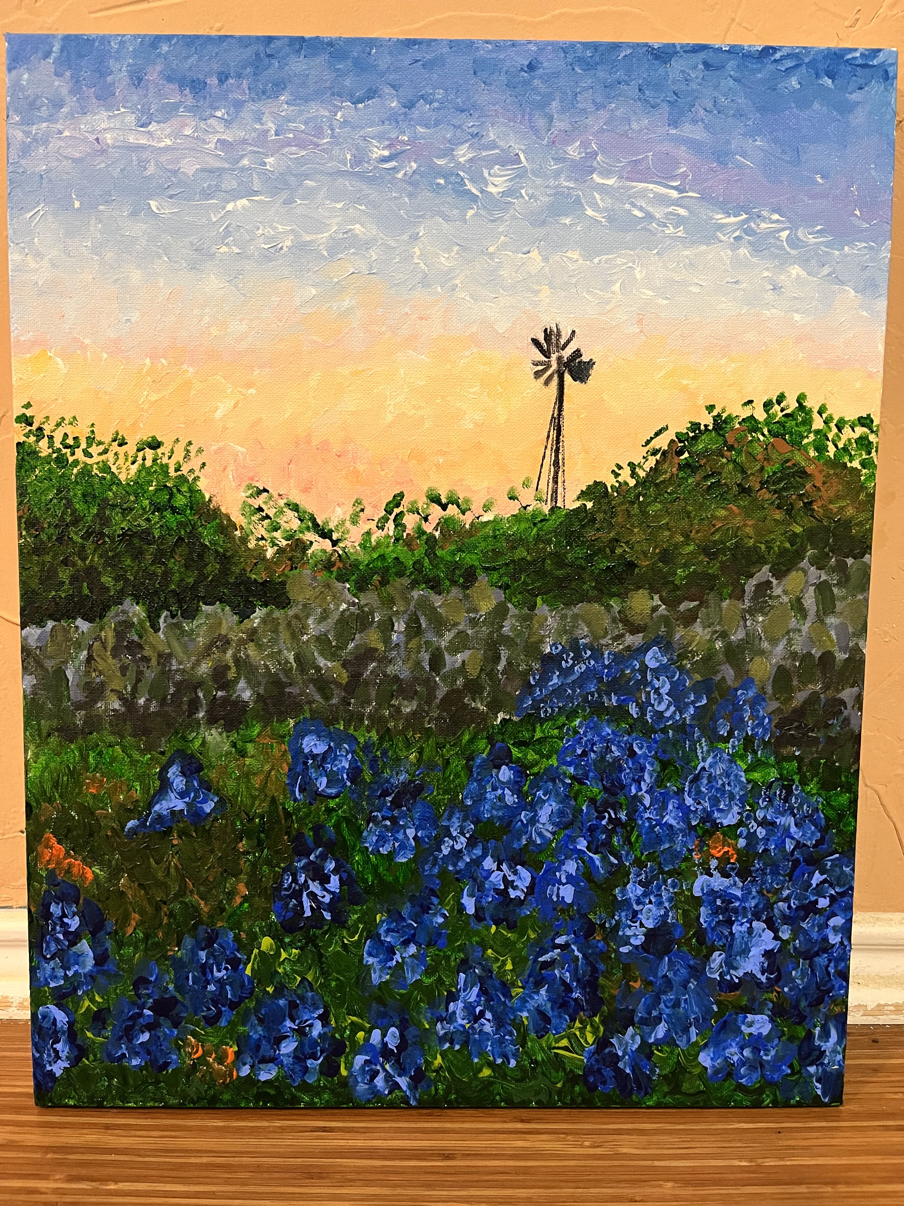 A field of bluebonnets in front of a windmill
